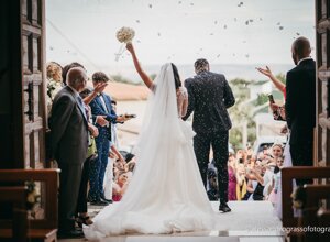 Bride and groom exiting church with guests celebrating confetti, Sicily wedding