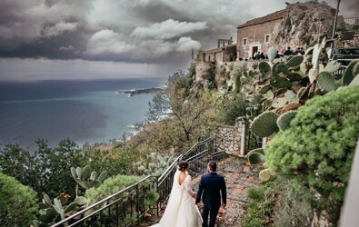 Luxury wedding couple walking along scenic Sicilian coast