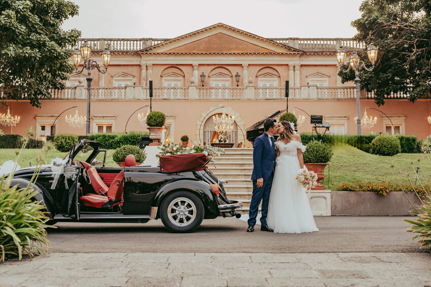 Couple kissing in front of a vintage car at a luxurious Sicily wedding venue