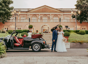 Bride and groom kissing in front of vintage car at a luxury villa wedding in Sicily