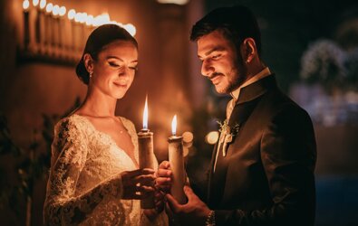 Bride and groom holding candles during a romantic Sicilian wedding ceremony.