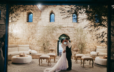 Luxury Sicilian wedding couple kissing in elegant historic venue.