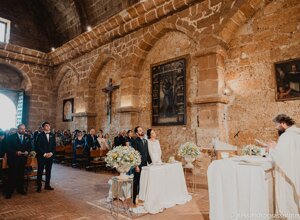 Wedding ceremony in a historic Sicilian church with a priest and guests.