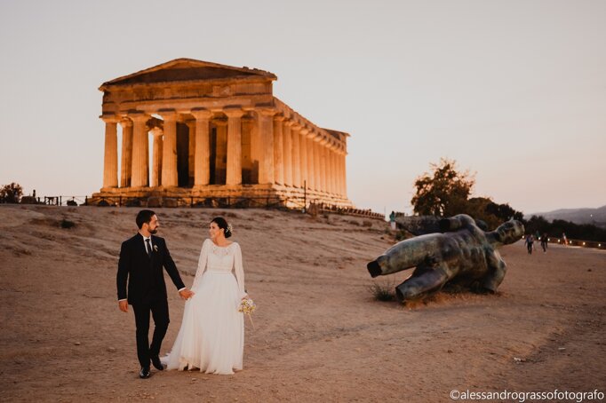 Bride and groom walking at sunset near Temple of Concordia in Agrigento, symbolizing a luxury Sicilian destination wedding.