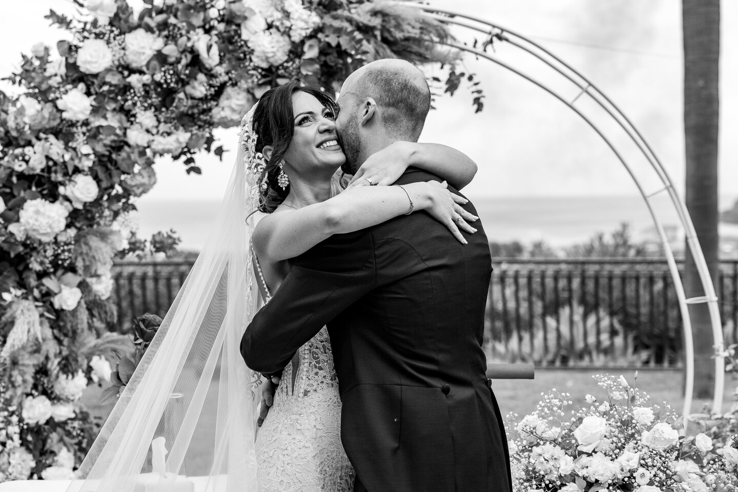 Couple embracing at a luxury Sicilian wedding with floral arch
