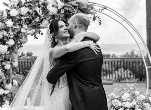 Bride and groom embracing under floral arch during Sicily wedding ceremony