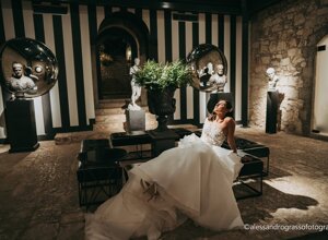 Bride in elegant setting with classical statues and striped walls, Sicily weddings.
