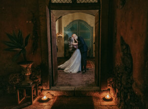 A couple sharing a romantic kiss at their luxury wedding in Sicily, surrounded by warm candlelight.