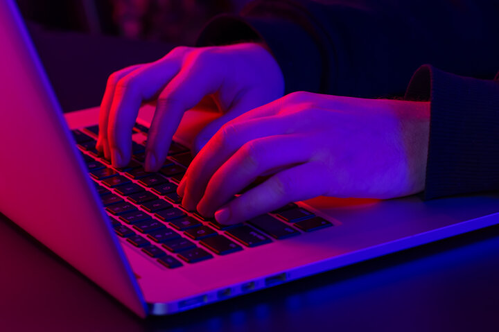 man-uses-laptop-closeup-male-hands-neon-lighting.jpeg