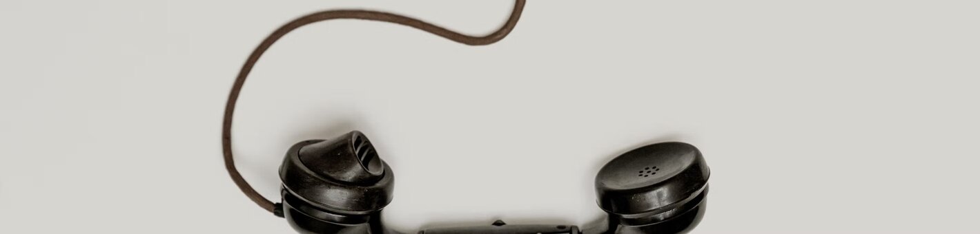 Vecchia cornetta telefonica con filo su sfondo grigio