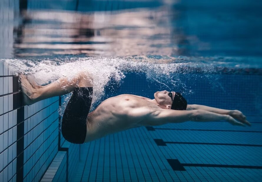 Nuotatore sott'acqua spinge muro piscina, sport e traumi sportivi Nuotatore sott'acqua spinge muro piscina, sport e traumi sportivi