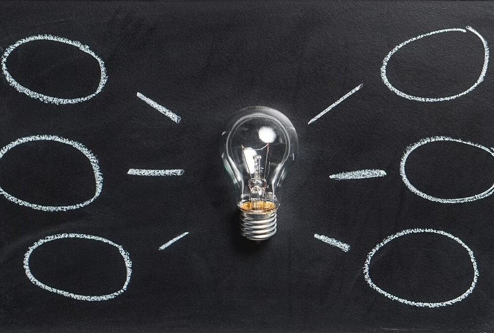 Lampadina su lavagna nera con diagramma disegnato a gesso