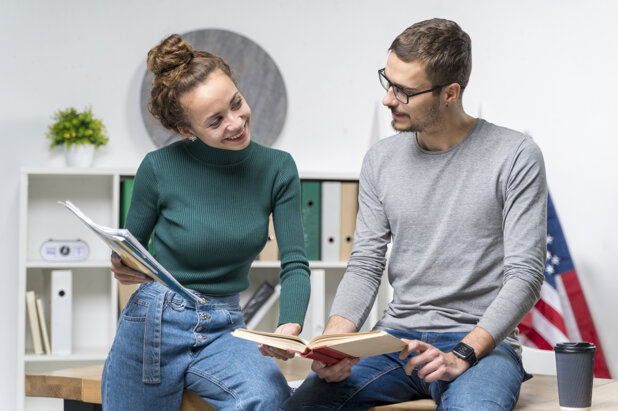 Due persone leggono e studiano insieme in un ambiente di ufficio.