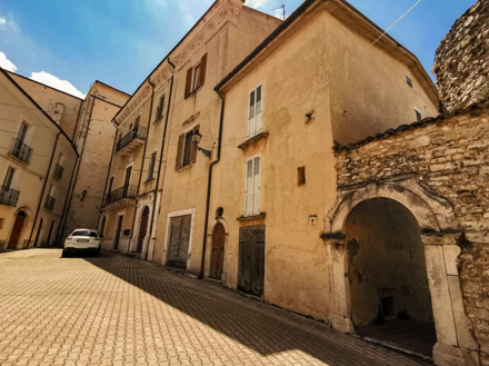Strada in un borgo storico con architettura tradizionale e auto parcheggiata