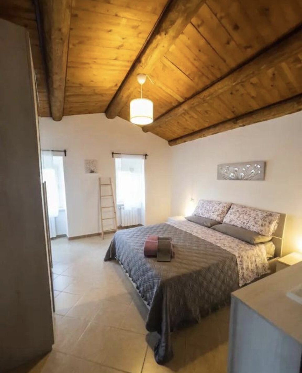 Camera da letto accogliente con soffitto in legno e arredamento moderno, ideale per soggiorno San Valentino