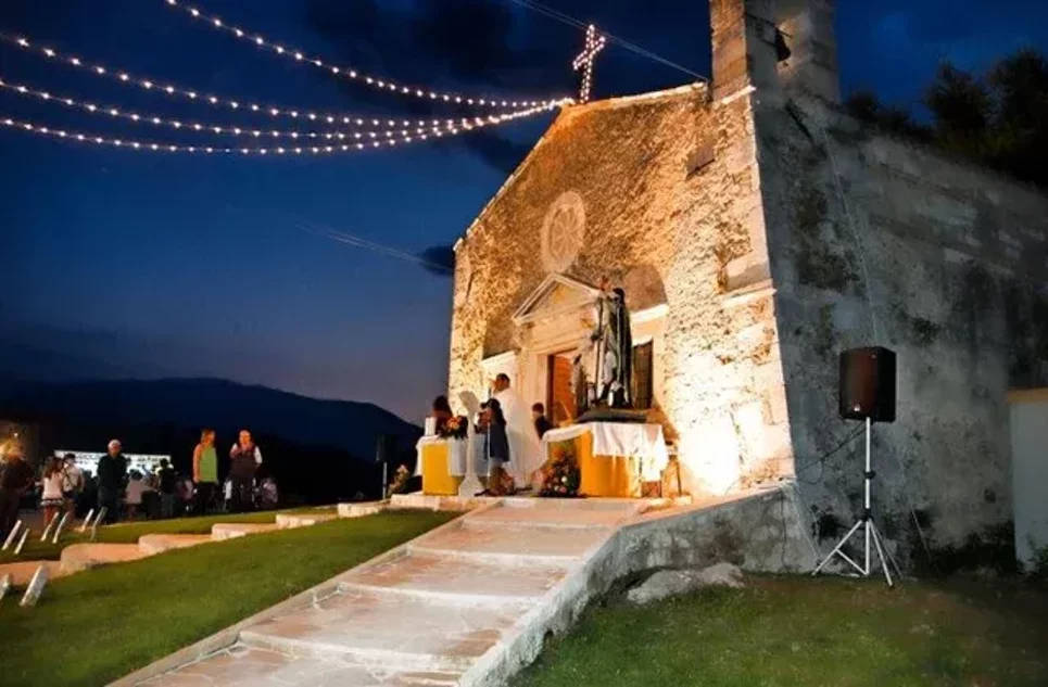 Festa serale presso la Chiesa di San Rocco illuminata, con persone e decorazioni luminose