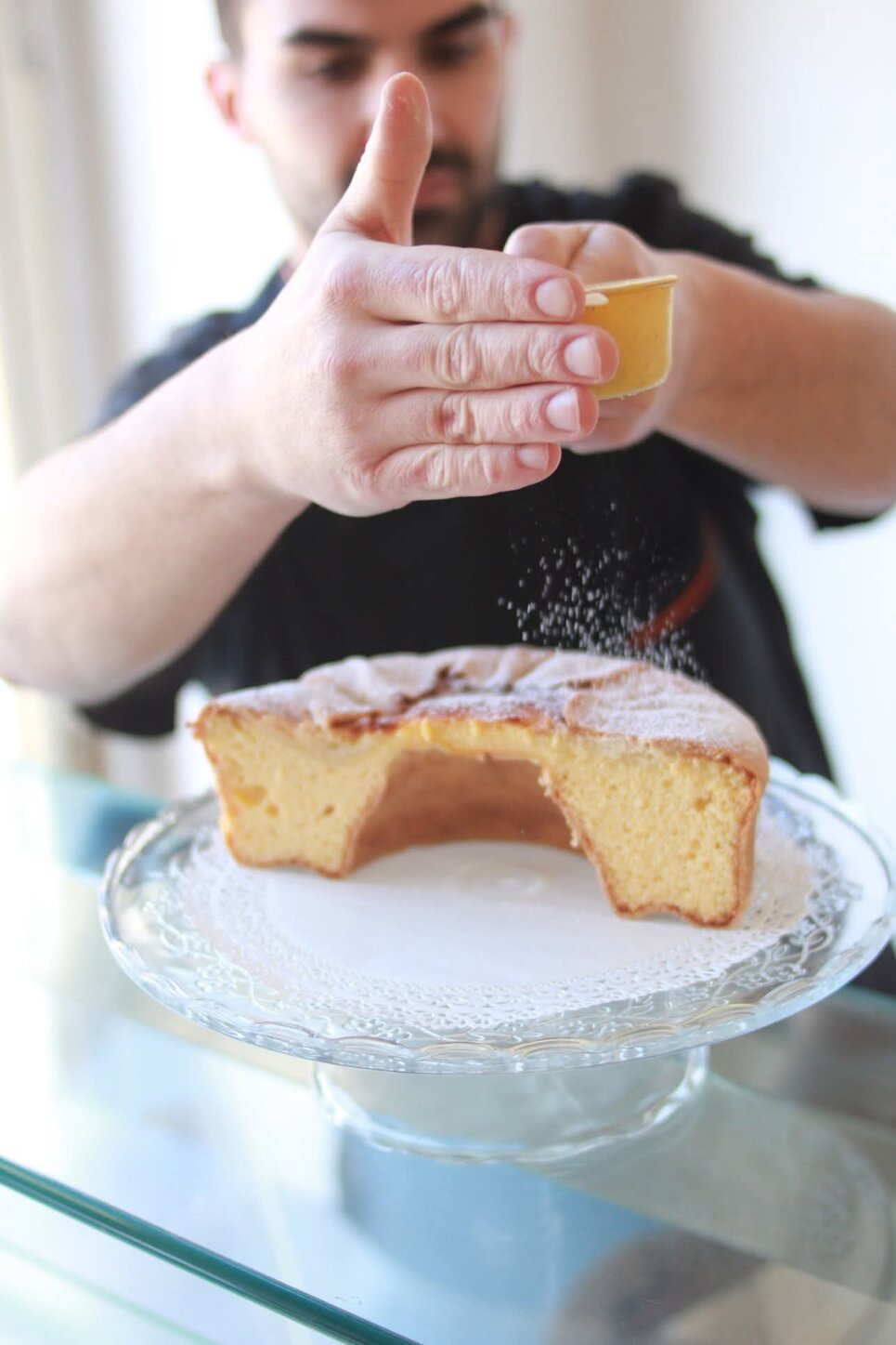Pasticcere spolvera zucchero su dolce abruzzese su alzata di vetro