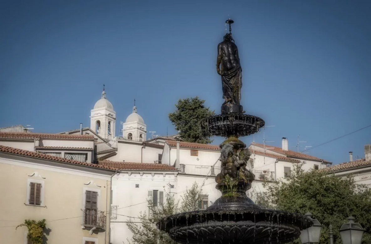 Fontana in un piazza con sfondo di edifici storici e cielo blu Fontana in un piazza con sfondo di edifici storici e cielo blu