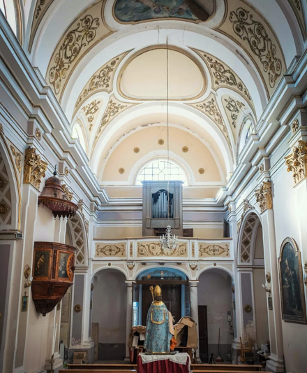 Interno di una chiesa storica con soffitto decorato e statua di un santo