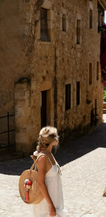 Donna che passeggia per una strada acciottolata vicino a un edificio in pietra