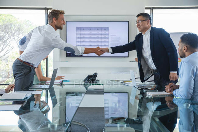 focused_413817188-stock-photo-asian-caucasian-businessman-standing-shaking.jpeg