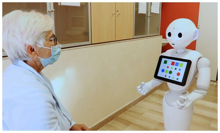 Robot umanoide interagisce con anziana in ambiente sanitario