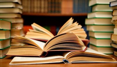 libros agrupados sobre una mesa y en estanterias de fondo
