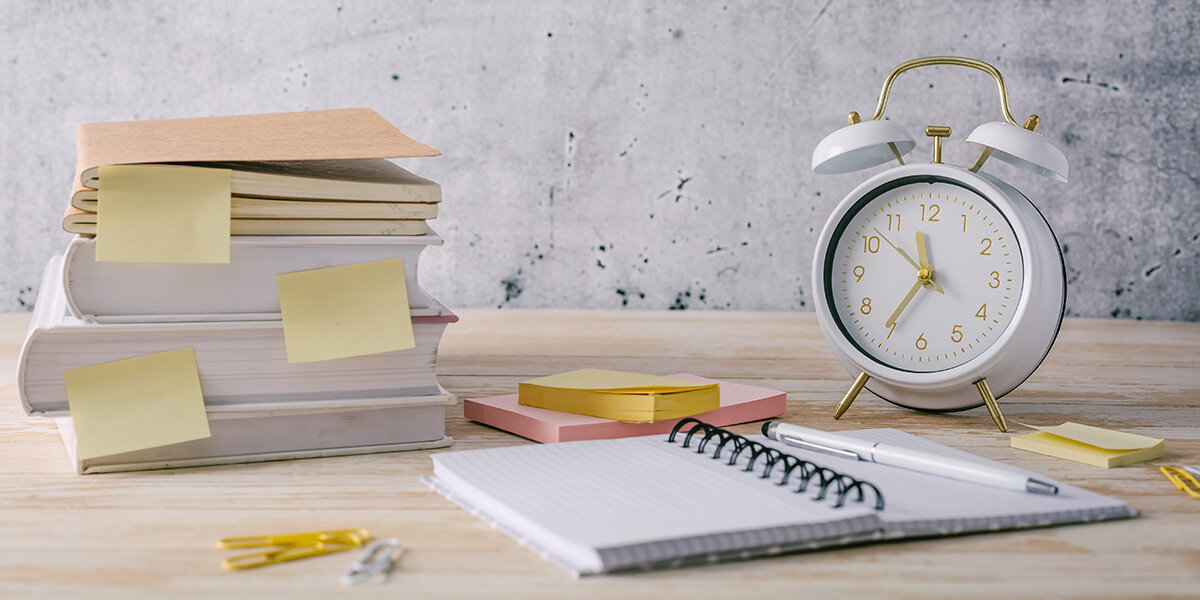 gestión-del-tiempo-y-planificación-de-tareas.jpeg libreta, libros con posit y reloj despertador