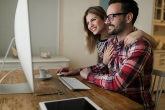 Coppia felice utilizza i servizi dell'agenzia immobiliare online ZeroCommissioni per cercare casa dal computer.