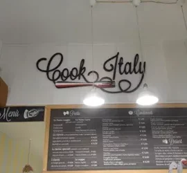 Insegna 'Cook Italy' sopra un menu in una cucina italiana.