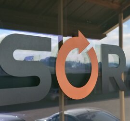 Adesivo vetrina con logo nero e arancione su vetro a Roma