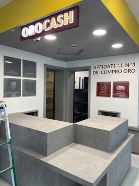 Interno di un negozio Compro Oro con insegna 'ORO CASH' e bancone moderno Interno di un negozio Compro Oro con insegna 'ORO CASH' e bancone moderno