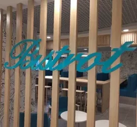 Allestimento interno di un locale con divisoria in legno e scritta decorativa.