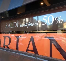Vetrina di negozio con promozione saldi sconti fino al 50%