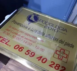 Targa di uno studio podologico con informazioni di contatto.