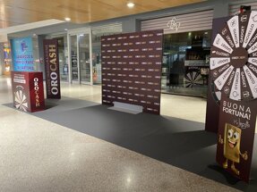 Allestimento inaugurale OroCash in un centro commerciale con pannelli e ruota della fortuna.