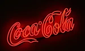 Insegna al neon rossa con il logo Coca-Cola su sfondo scuro