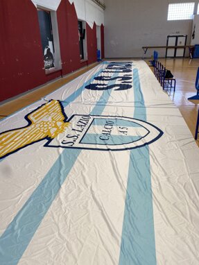 Striscione di una squadra di calcio in palestra con stemma e colori bianco e azzurro