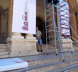 Preparazione allestimento evento IEEE con poster e impalcatura su gradini di un edificio storico