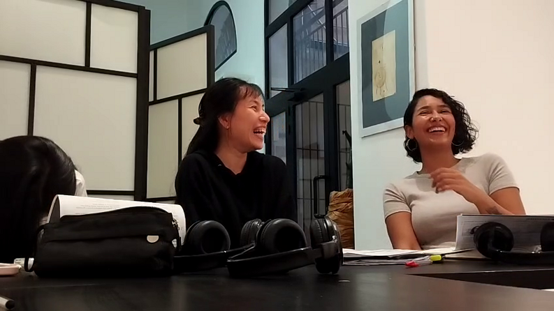 Students laughing during a language learning class with books and headphones.