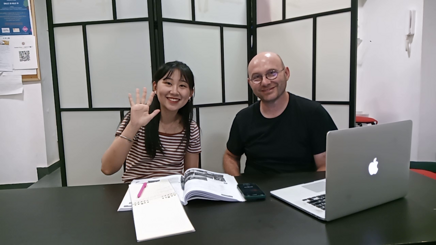 Students engaging in language learning session with books and laptop.