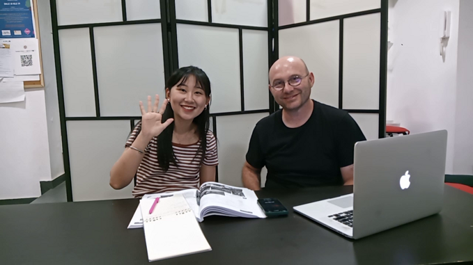 Italian language learning session with two people, working on a laptop and books.