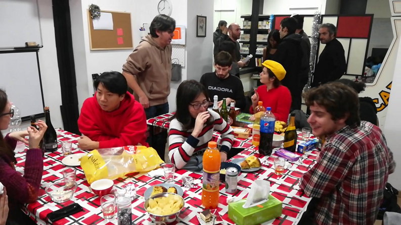 Group of people enjoying a social event at an art school, with snacks and drinks on the table.