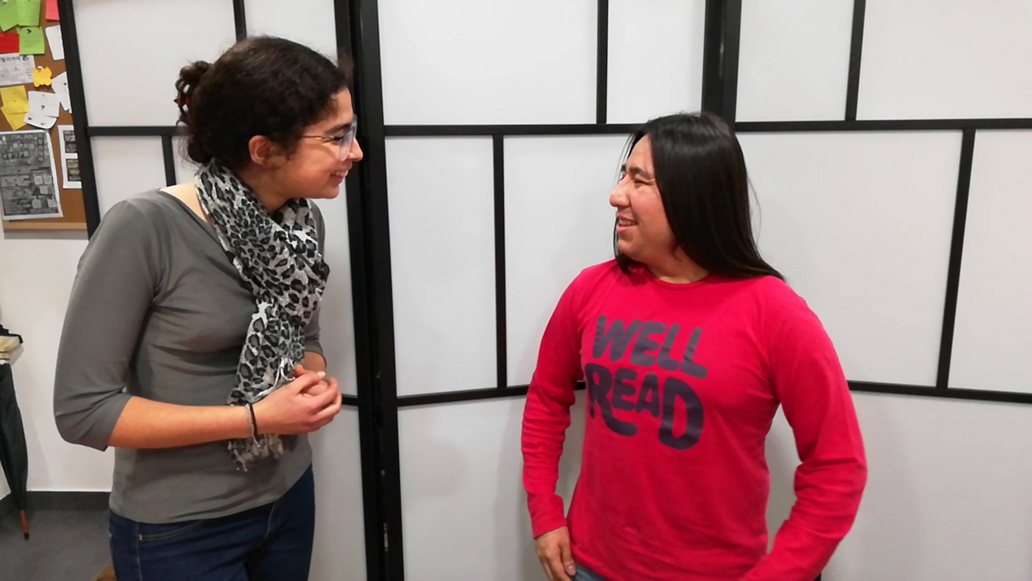Two people smiling and talking at an educational setting.