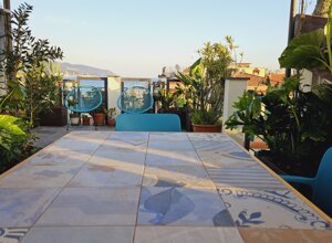 Terrazzo tropicale con piante e sedie blu, vista mare