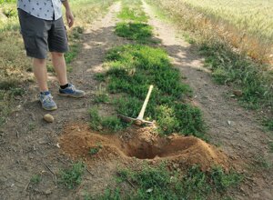 Persona in piedi su un sentiero di terra con un piccone vicino a una buca Persona in piedi su un sentiero di terra con un piccone vicino a una buca