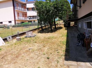 Giardino privato con attrezzi da giardinaggio e palazzi residenziali sullo sfondo