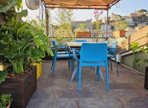 Terrazzo tropicale con sedie blu e piante verdi, vista panoramica di una città