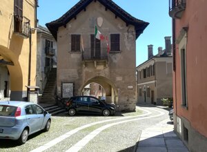 Strada acciottolata di Vogogna con edifici storici, bandiere italiane e cielo sereno. Strada acciottolata di Vogogna con edifici storici, bandiere italiane e cielo sereno.