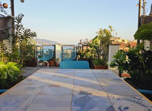 Terrazzo tropicale con piante verdi e sedie blu vista mare